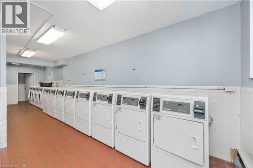 Lounge with multiple front-loading washers and dryers, terracota tile flooring, and fluorescent lighting - 975 Warwick Court Unit# 708, Burlington, ON - Indoor Photo Showing Laundry Room