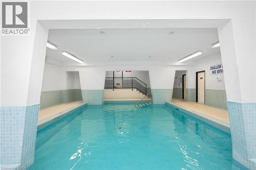 Indoor swimming pool with light blue tiled surround, white walls, and bright overhead lighting - 975 Warwick Court Unit# 708, Burlington, ON - Indoor Photo Showing Other Room With In Ground Pool