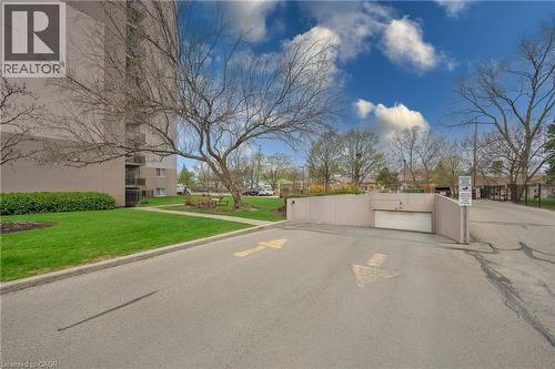 Underground parking entrance with directional arrows, paved driveway, and manicured lawn - 975 Warwick Court Unit# 708, Burlington, ON - Outdoor