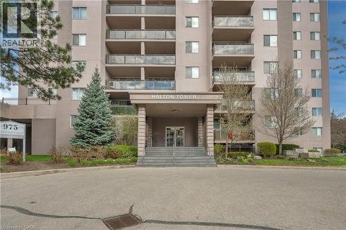 High-rise building with a grand entrance featuring stone columns, a covered entryway, and multi-level balconies with glass railings - 975 Warwick Court Unit# 708, Burlington, ON - Outdoor With Balcony With Facade