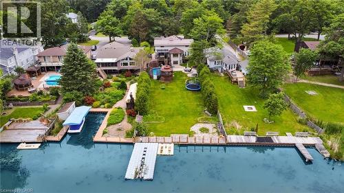 Waterfront property featuring extensive private docks, a covered boat slip, a tiered backyard with mature landscaping, and a substantial in-ground swimming pool - 247 Sand Road, Holland Landing, ON - Outdoor With Body Of Water