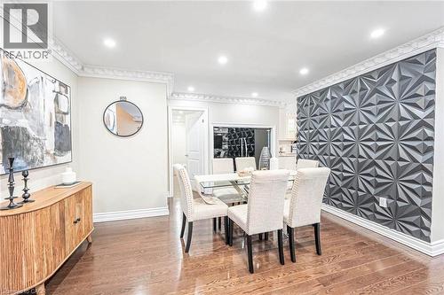 Dining area featuring a prominent textured accent wall, rich wood-finish flooring, recessed lighting, crown molding, and substantial baseboards - 247 Sand Road, Holland Landing, ON - Indoor Photo Showing Dining Room