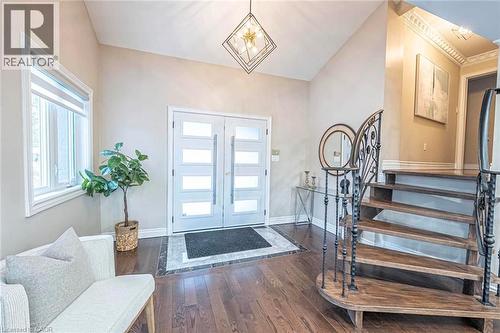 Entryway featuring double doors with frosted glass panels, dark wood-finish flooring, a grand staircase with an ornate wrought-iron railing, vaulted ceilings, and a contemporary light fixture - 247 Sand Road, Holland Landing, ON - Indoor Photo Showing Other Room