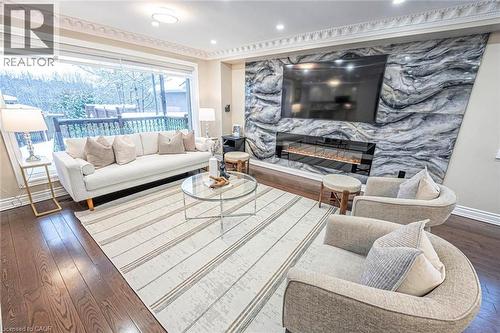 Living area featuring expansive window, hardwood flooring, detailed crown molding, a contemporary fireplace with a linear insert, and a striking stone-paneled accent wall - 247 Sand Road, Holland Landing, ON - Indoor Photo Showing Living Room With Fireplace