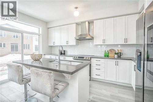 Modern kitchen featuring white cabinetry, subway tile backsplash, stainless steel appliances, a center island with an undermount sink, and wood-finish flooring - 525 Red Elm Road, Shelburne, ON - Indoor Photo Showing Kitchen