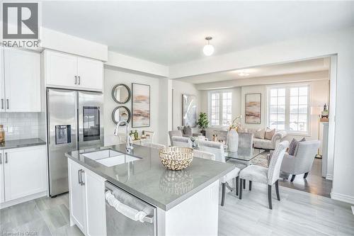 Open concept living space featuring a kitchen island with sink, white shaker cabinetry, stainless steel appliances, and large windows - 525 Red Elm Road, Shelburne, ON - Indoor Photo Showing Kitchen With Upgraded Kitchen