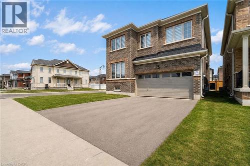 Brick exterior with a two-car garage, asphalt driveway, and concrete sidewalk - 525 Red Elm Road, Shelburne, ON - Outdoor With Facade