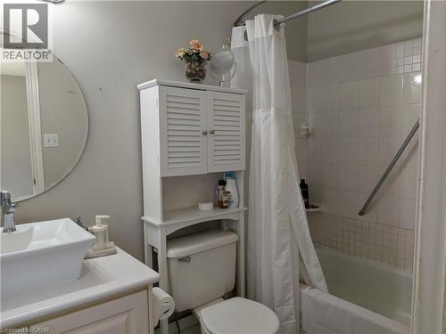 White vessel sink with chrome faucet, white countertop, white built-in storage cabinet, white toilet, and white tiled shower surround with a grab bar - 45 Caswell Drive Unit# Upper, Hamilton, ON - Indoor Photo Showing Bathroom