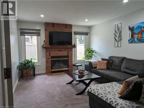 Recessed ceiling lighting, brick fireplace with wood mantel, multiple windows, and light gray wall paint - 45 Caswell Drive Unit# Upper, Hamilton, ON - Indoor Photo Showing Living Room With Fireplace
