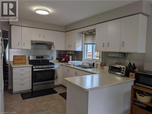 Kitchen featuring white cabinetry, light-toned countertops, a stainless steel range, and a stainless steel range hood - 45 Caswell Drive Unit# Upper, Hamilton, ON - Indoor Photo Showing Kitchen With Double Sink