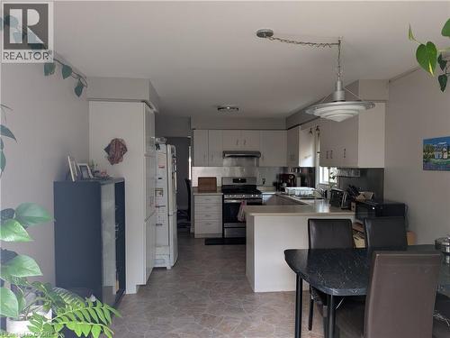 Kitchen featuring light-toned cabinetry, stainless steel range with overhead hood, and a peninsula countertop - 45 Caswell Drive Unit# Upper, Hamilton, ON - Indoor