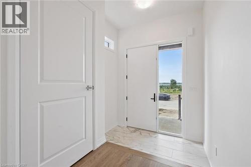 Entryway featuring a white paneled door, wood-finish flooring, and a white tile floor - 451 Benninger Street, Kitchener, ON 