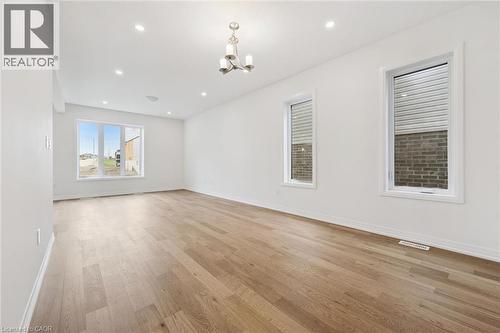 Spacious room featuring wood-finish flooring, recessed lighting, and a contemporary chandelier - 451 Benninger Street, Kitchener, ON 
