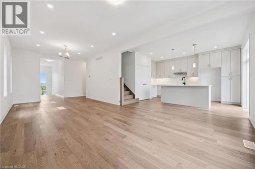 Open-concept living space featuring wood-finish flooring, recessed lighting, and a modern kitchen with white cabinetry, a central island, and pendant lighting - 451 Benninger Street, Kitchener, ON 