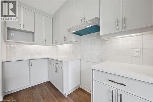 White cabinetry with chrome hardware, smooth surface countertops, and an integrated range hood - 451 Benninger Street, Kitchener, ON 