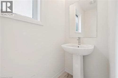 Pedestal sink with chrome faucet, large wall-mounted mirror, and white trim window - 451 Benninger Street, Kitchener, ON 
