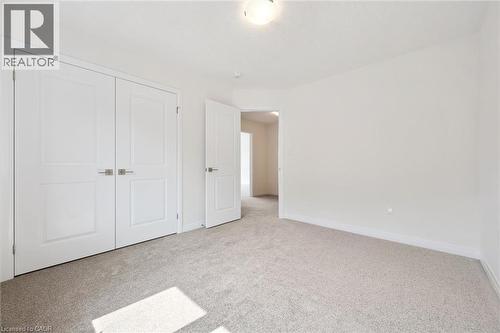 Neutral tone wall paint, light-colored carpet flooring, recessed ceiling light fixture, and paneled interior doors with brushed nickel hardware - 451 Benninger Street, Kitchener, ON 