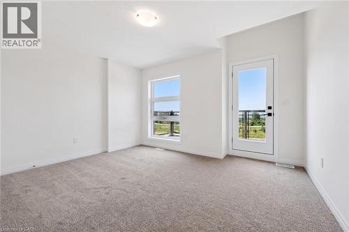 Carpeted room featuring a white interior, a modern window, a glass-paned door, and a flush-mount ceiling light - 451 Benninger Street, Kitchener, ON 