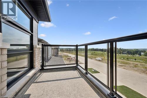 Private balcony with glass panel railing, concrete flooring, and exterior brick detailing - 451 Benninger Street, Kitchener, ON 