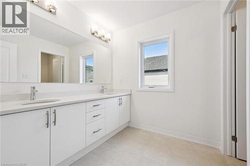 Dual vanity with integrated sinks, white cabinetry, chrome hardware, and a large wall-mounted mirror - 451 Benninger Street, Kitchener, ON 
