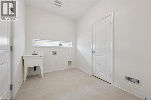 Ceramic tile flooring, white utility sink, horizontal window, and white interior doors - 451 Benninger Street, Kitchener, ON 