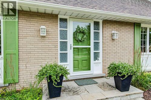 Brick exterior featuring a vibrant green entry door with a storm door, flanked by decorative sidelights and green louvered shutters - 97 Somerset Crescent, Waterloo, ON - Outdoor With Exterior