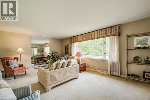 Spacious living area featuring a large picture window, a built-in fireplace with a mirrored surround, and wall-to-wall carpeting - 97 Somerset Crescent, Waterloo, ON - Indoor Photo Showing Living Room