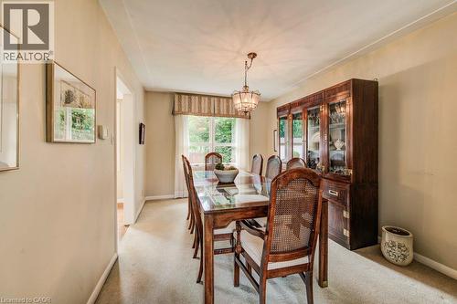 Carpeted dining area with a glass-top table, chandelier lighting, and a built-in wood-finish display cabinet with glass doors - 97 Somerset Crescent, Waterloo, ON - Indoor Photo Showing Dining Room