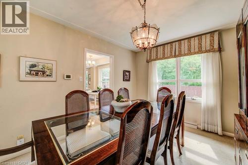 Dining area featuring a decorative chandelier, crown molding, and a large window with privacy sheers - 97 Somerset Crescent, Waterloo, ON - Indoor Photo Showing Dining Room