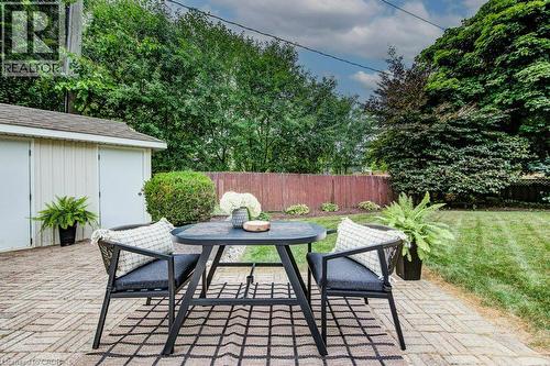 Expansive backyard patio featuring brick paver flooring, a detached shed with double doors, a manicured lawn, and mature perimeter trees - 97 Somerset Crescent, Waterloo, ON - Outdoor With Deck Patio Veranda