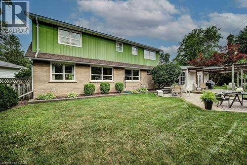 Expansive grassy yard area with a paved patio featuring a pergola - 97 Somerset Crescent, Waterloo, ON - Outdoor