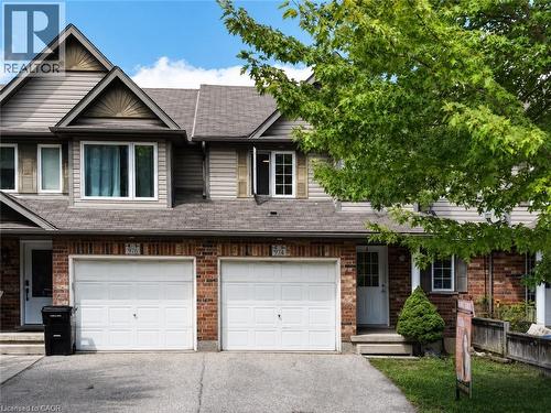 Brick and siding exterior featuring gabled rooflines, multiple windows, and a white garage door - 974 Creekside Drive, Waterloo, ON - Outdoor With Facade