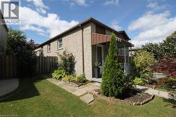 Brick exterior with covered front entry, mature landscaping, paved walkway, and fenced rear yard - 