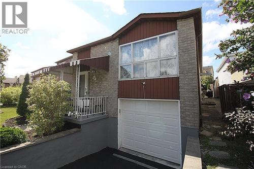 Brick exterior with brown siding accents, attached garage, covered front entry, and mature landscaping - 35 Garden Crescent, Hamilton, ON - Outdoor With Exterior