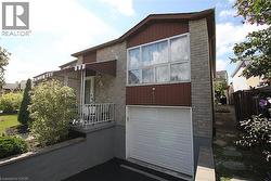 Brick exterior with brown siding accents, attached garage, covered front entry, and mature landscaping - 