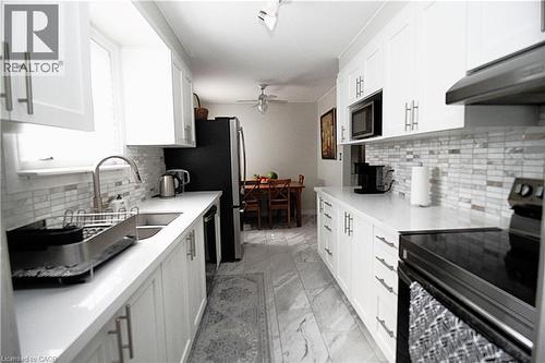 Galley kitchen with white shaker-style cabinetry, stainless steel sink, and light-toned countertops - 35 Garden Crescent, Hamilton, ON - Indoor Photo Showing Kitchen With Upgraded Kitchen