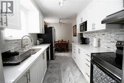 Galley kitchen with white shaker-style cabinetry, stainless steel sink, and light-toned countertops - 