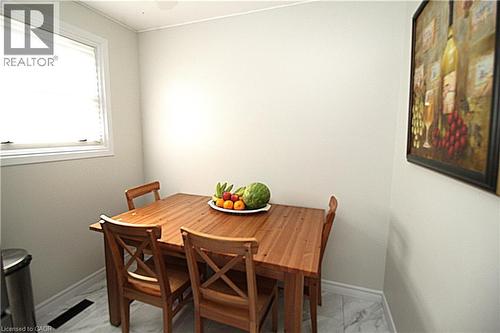 White-framed window with blinds, light-colored walls, white baseboards, and patterned floor tile - 35 Garden Crescent, Hamilton, ON - Indoor Photo Showing Dining Room