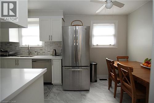 White cabinetry, tile backsplash, stainless steel appliances, white countertops, and tile flooring - 35 Garden Crescent, Hamilton, ON - Indoor Photo Showing Kitchen