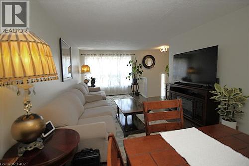 Spacious living area featuring a large window with sheer curtains, wood-finish flooring, and light-colored walls - 35 Garden Crescent, Hamilton, ON - Indoor Photo Showing Living Room