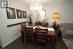 Dining area featuring wood-finish flooring, a crystal chandelier, and a decorative wall shelf - 