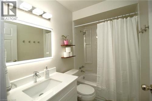 White vanity with integrated sink, chrome faucet, and backlit mirror - 35 Garden Crescent, Hamilton, ON - Indoor Photo Showing Bathroom