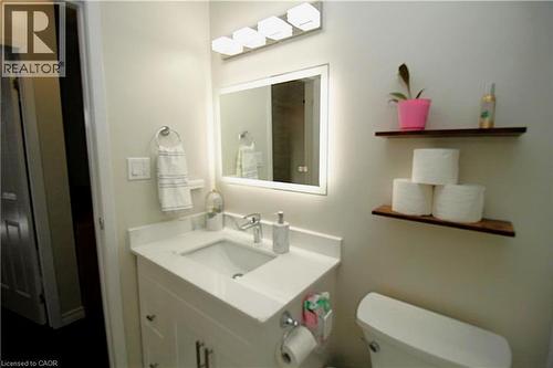 White vanity with an integrated sink, polished chrome faucet, and a rectangular mirror with integrated lighting - 35 Garden Crescent, Hamilton, ON - Indoor Photo Showing Bathroom