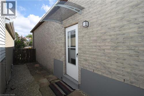 Brick exterior with a clear entry awning, exterior wall light, and a glass-paneled door - 35 Garden Crescent, Hamilton, ON - Outdoor With Exterior