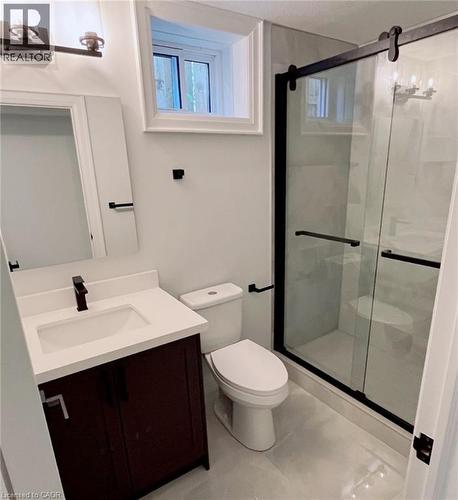 Vanity with a white countertop and integrated sink, matte black faucet, and dark wood-finish cabinetry - 81 Second Avenue Unit# B, Kitchener, ON - Indoor Photo Showing Bathroom