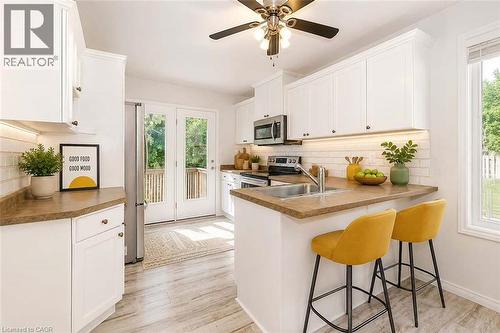 Kitchen featuring white cabinetry, light wood-finish flooring, a stainless steel sink, a window, and double french doors - 47 Queensway Drive, Strathroy, ON - Indoor Photo Showing Kitchen With Double Sink