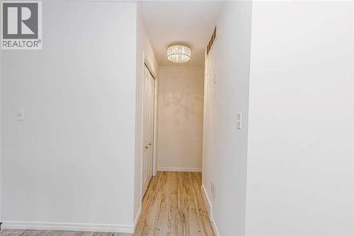 Hallway featuring wood-finish flooring, white walls, and a contemporary ceiling light fixture - 47 Queensway Drive, Strathroy, ON - Indoor Photo Showing Other Room
