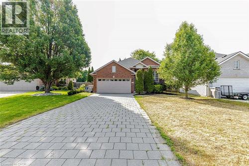 Brick exterior featuring a paver driveway, attached garage, and mature trees - 47 Queensway Drive, Strathroy, ON - Outdoor