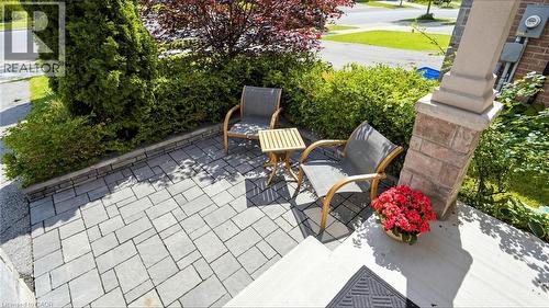 Paver stone patio with a retaining wall, accented by lush landscaping and a stone-clad column - 173 Raymond Road, Ancaster, ON - Outdoor