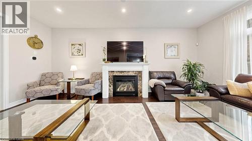 Warm living space featuring rich wood-finish flooring, a contemporary fireplace with a stone surround, and a classic white mantel - 173 Raymond Road, Ancaster, ON - Indoor Photo Showing Living Room With Fireplace